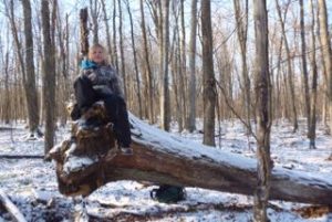 Photo of Macoun Club member Avalon McCabe perched on her toppled Study Tree, a Red Oak