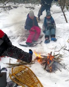 Photo of Macoun Club kids at a winter campfire, cold foot extended to warm up