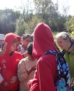 Photo of Macoun Club group -- kids, leaders, and parents, crowding around to see what's been found (snake? salamander? beetle?)